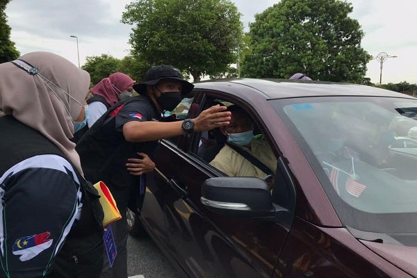 Para petugas dalam kalangan pelajar memberi panduan kepada ibu bapa yang hadir bersama pelajar baharu