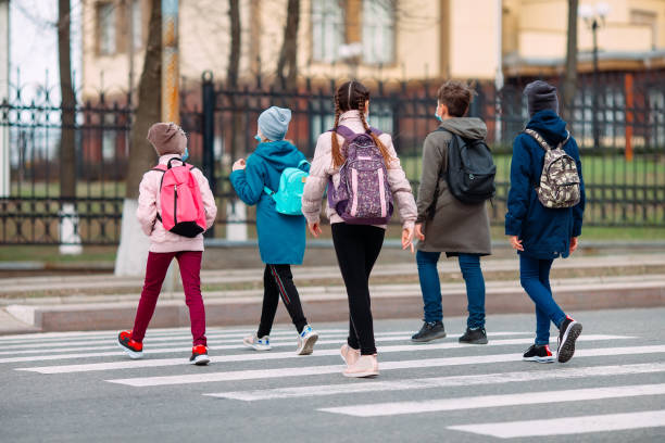 School children cross the road in medical masks. Children go to school