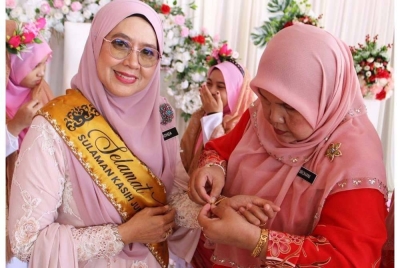 Cikgu Rohida menerima hadiah rantai tangan daripada warga sekolah.