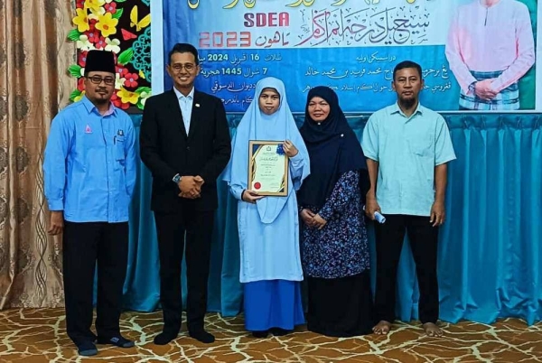 Mohd Fared (dua dari kiri) selepa menyampaikan sijil kepada pelajar cemerlang, Mufidah Muhamad Saleh dalam Majlis Pengisytiharan Keputusan Peperiksaan SDEA di Sekolah Agama Bandar Kota Tinggi, Kota Tinggi pada Selasa.