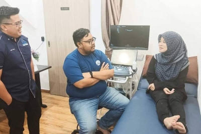 Abdul Hafiz Faizal (kiri) bersama Dr Anwar Asyraff Abdul Aziz (tengah) mendengar sesuatu yang dinyatakan seorang pesakit. 