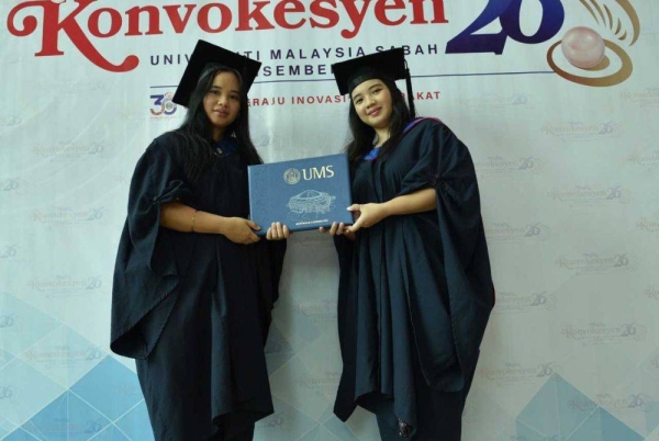 Jaynie (kiri) dan Janet (kanan) menerima skrol ijazah masing-masing dalam Majlis Konvokesyen UMS kali ke-26. 
