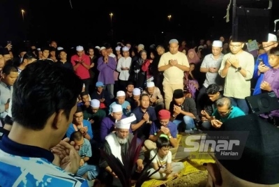 Muhammad (duduk paling hadapan) membacakan talkin sejurus pengebumian Allahyarham Cikgu E di Tanah Perkuburan Islam Meru Raya. 