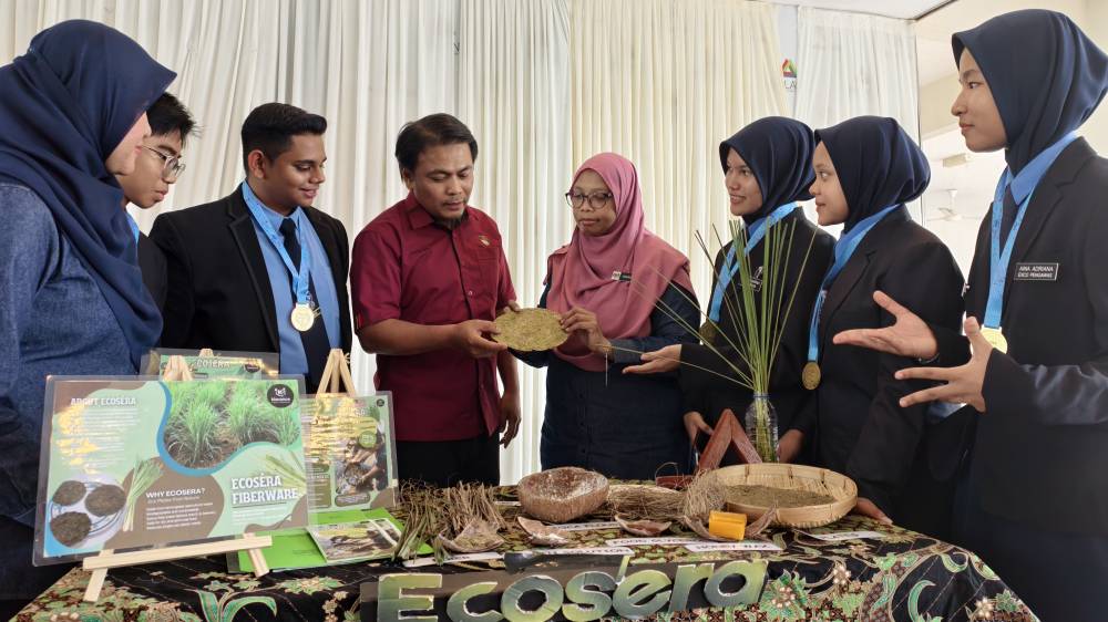 Cikgu Noor Shariffah (empat dari kanan) menerangkan projek pinggan biodegrasi daripada daun serai.