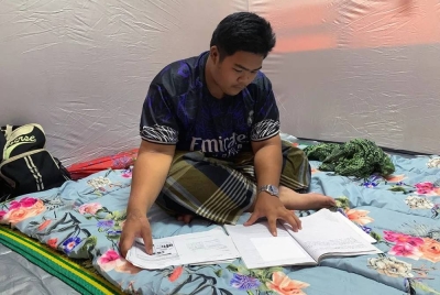 Wan Muhammad Radhi tetap bersemangat mengulang kaji pelajaran biarpun menjadi mangsa banjir. 