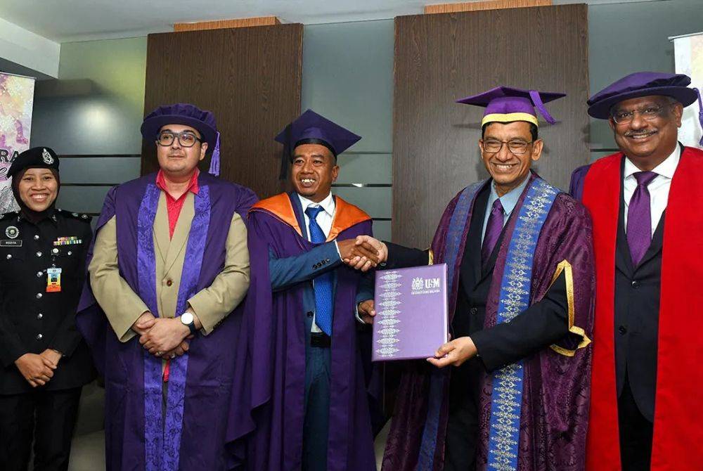 Abdul Rahman (dua, kanan) mengucap tahniah kepada Mohd Khairul yang menerima Ijazah Sarjana Sains Kemasyarakat pada Sidang Ketiga Upacara Konvokesyen Ke-63 USM.