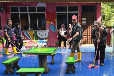 Kamsah @ Kamal (dua kanan) bersama guru membersihkan kawasan sekolah yang terjejas banjir. 