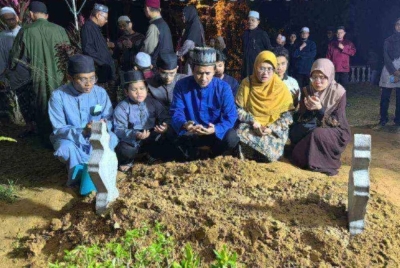 Mazli (tengah) bersama isteri dan enam anaknya di pusara Allahyarhamah Syakirah Hanan selepas selesai pengebumian di Tanah Perkuburan Islam Kubur Besar Kuala Bedah, di Kuala Terengganu sekitar jam 12.30 tengah malam pada Isnin. 