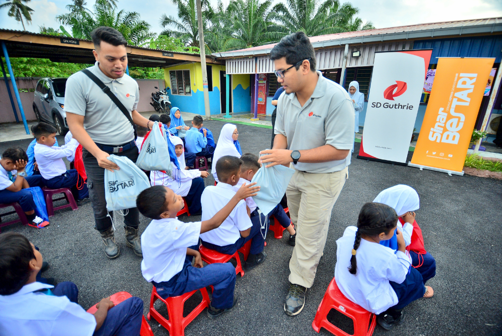 Wakil SD Guthrie mengedarkan beg Sinar Bestari kepada murid-murid.