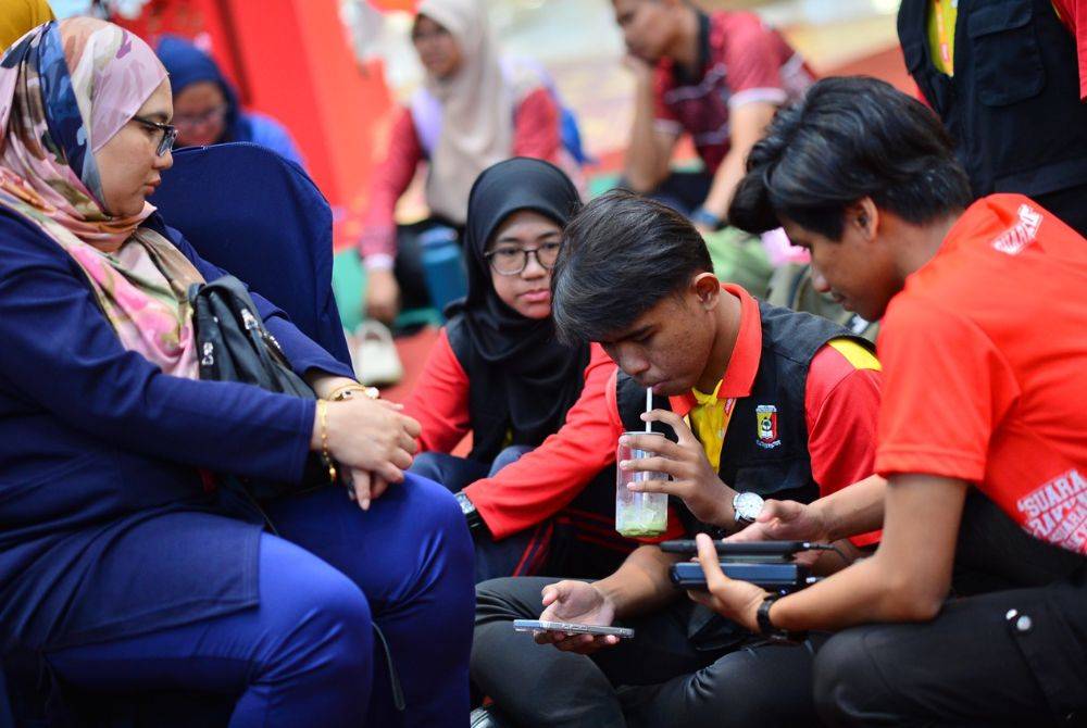 Muhammad Iskandar Shafwan (dua dari kanan) dan pasukan memulakan suntingan video dengan bimbingan guru.
