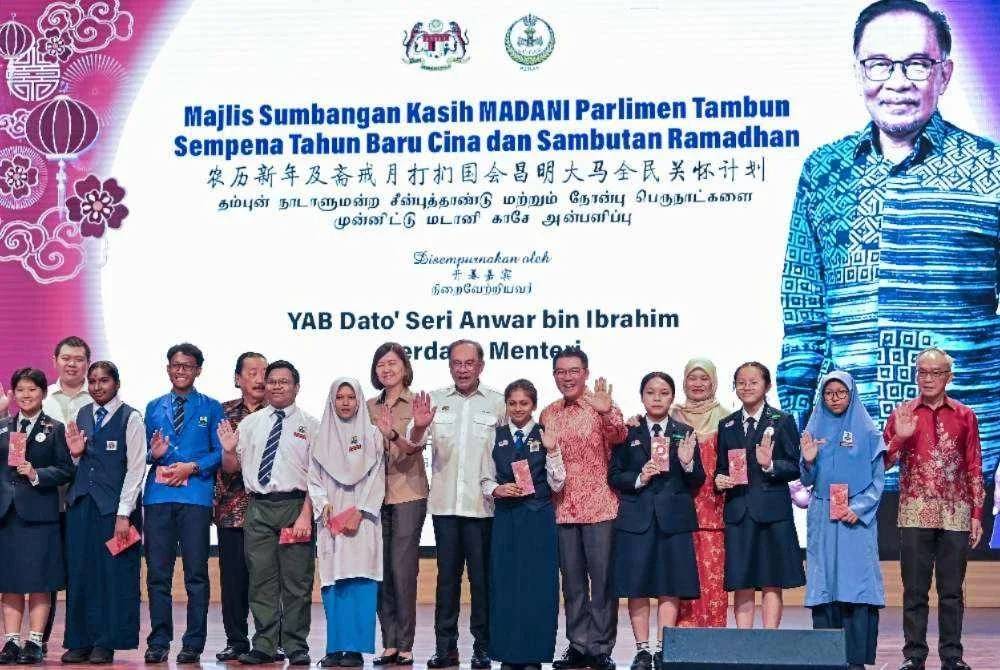 Anwar (tengah) bersama pelajar pada Majlis Sumbangan Kasih Madani Parlimen Tambun Sempena Tahun Baharu Cina dan Sambutan Ramadan di Dewan Tang Ying See, Sekolah Menengah Jenis Kebangsaan Yuk Choy, Ipoh pada Sabtu. 