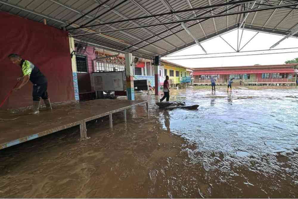 Guru dan kakitangan SK Kemabong, Tenom membersihkan kawasan sekolah selepas air mulai surut.