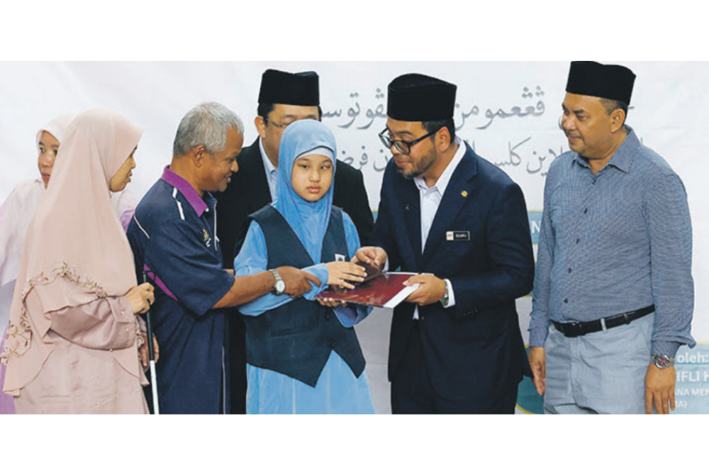 Menteri di Jabatan Perdana Menteri (Hal Ehwal Agama), Dr Zulkifli Hasan (dua dari kanan) menyampaikan penghargaan kepada Nurul Aina Solehah yang meraih keputusan cemerlang dalam UPKK, sambil disaksikan ibu bapanya.