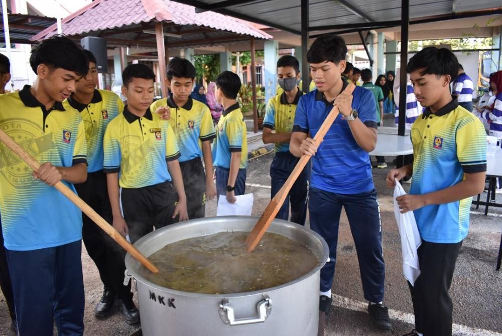 Kumpulan pelajar SMK Kota Kemuning mengacau bubur lambuk dalam Program Santunan Bubur Lambuk 3.0 pada Selasa.
