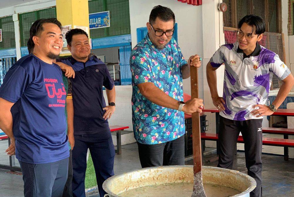 Hedrhin Ramli (baju biru) bersama-sama guru SK Pandamaran Jaya menyiapkan bubur lambuk untuk diagihkan.