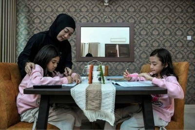 Shahira membantu dua anak saudaranya, Khayla Zahra Mohd Zahir, 11, dan Khayla Zulfa Mohd Zahir, 9, menjalani PdPR.