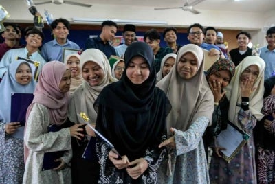 Huda Rasheeda (tengah) bersama rakan-rakan sambil menunjukkan keputusan 10A dalam SPM. 
