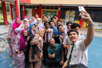 Tengku Zafrul (duduk di tengah) berkongsi gambar bersama pelajar sebuah sekolah di laman Facebooknya dengan kapsyen 'Macam mana result SPM anak-anak hari ini? Harapnya ramai yang happy'. 