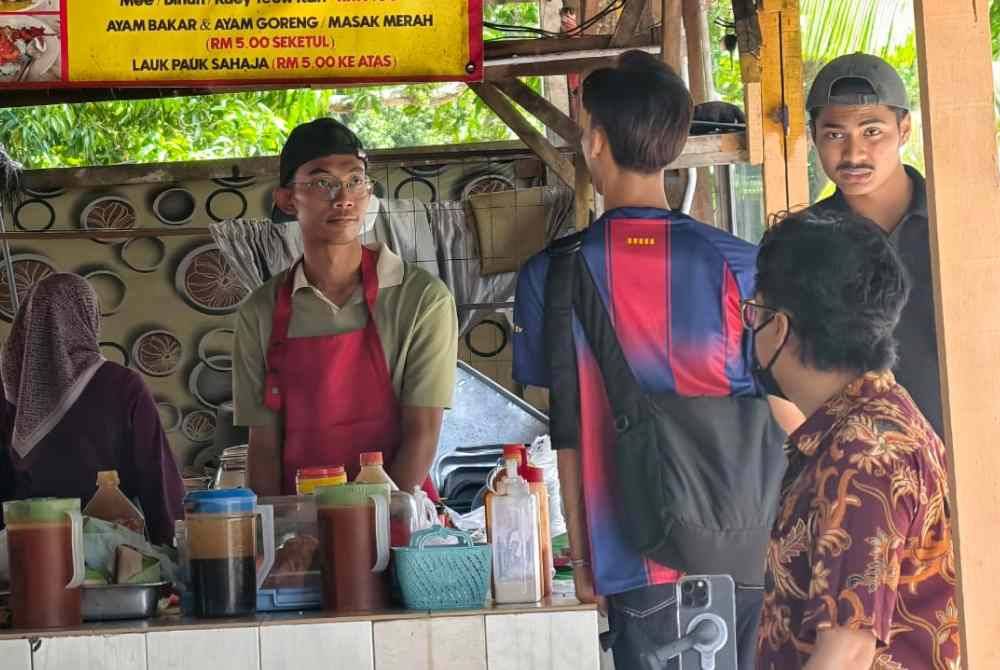 Fakhrul Iman melayani pelanggan di gerai ibu bapanya yang menjadi punca pendapat mereka sekeluarga.