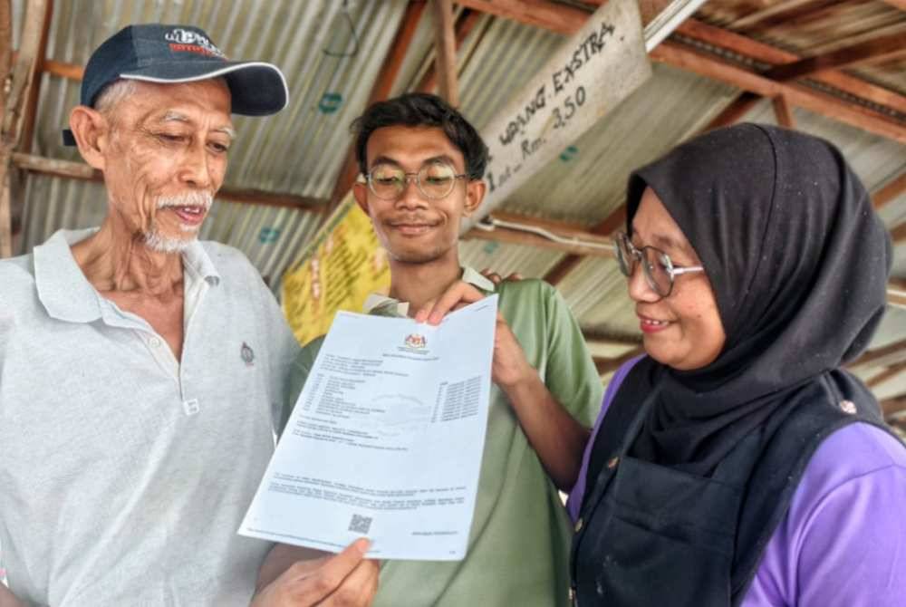 Fakhrul Iman (tengah) menunjukkan slip keputusan SPM 2025 kepada ibu bapanya.