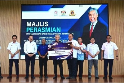 Ahmad Zahid (empat dari kiri) menyerahkan cek cura bernilai RM650,000 bagi membantu membaik pulih infrastruktur di MRSM Tun Ghafar Baba.