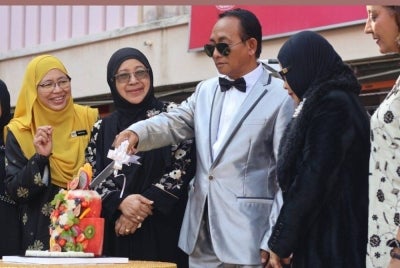 Cikgu Mohd Fauzi (tengah) memotong kek sebagai simbolik meraikan majlis persaraannya yang berlangsung penuh meriah pada Khamis. 