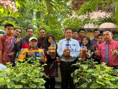 Mohd Rosli (depan, kiri) dan Kamarul Zaman (tengah) bersama pelajar menunjukkan hasil madu kelulut yang diperoleh.