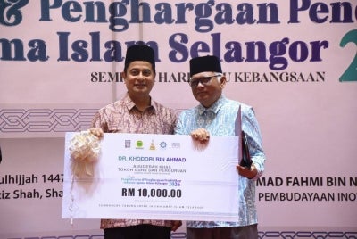 Dr Khodori (kanan) menerima Anugerah Tokoh Khas Guru dan Perguruan daripada Mohammad Fahmi (kiri) dalam Majlis Pengiktirafan dan Penghargaan Pendidikan JAIS sempena Hari Guru Kebangsaan 2026. 