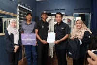 Adam Adli (dua dari kanan) menyerahkan surat BAeK PTPTN kepada salah seorang pelajar di Melaka, Muhammad Asymawi.