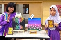 Nor Aisyah Nor Lazim (kiri) dan Nur Raisha Rania Abdullah bersama karya masing-masing yang memenangi Pertandingan Lukisan Kanvas PPKI Daerah Petaling Perdana.