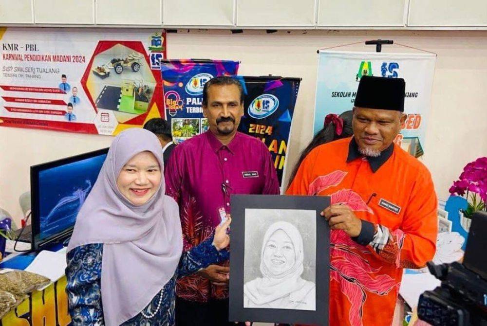 Ustaz Ahmad Bakhtier (kanan) menyampaikan cenderahati berupa potret kepada Menteri Pendidikan, Fadhlina Sidek (kiri) sempena Pameran KMR-PBL dalam Karnival Pendidikan Madani 2024 di Politeknik Seberang Perai, Pulau Pinang. 
