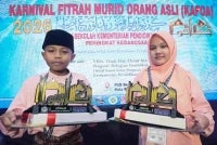 Johan hafazan al-Quran kategori lelaki dari Sekolah Kebangsaan (SK) Sungai Pusu, Muhamad Nazirul Hakim (kiri) dan johan hafazan al-Quran kategori perempuan (SK Gombak Utara), Nur Dalia Eryna bersama piala masing-masing pada Majlis Perasmian Penutup Karnival Fitrah Murid Orang Asli (KAFOA) Sekolah-Sekolah Kementerian Pendidikan Peringkat Kebangsaan Tahun 2026 di Pantai Cahaya Bulan, Kota Bharu, Kelantan. 