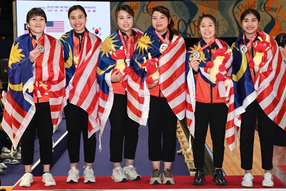 Adelia (kanan) bersama rakan sepasukan meraikan kemenangan bersama pingat dan Jalur Gemilang. 