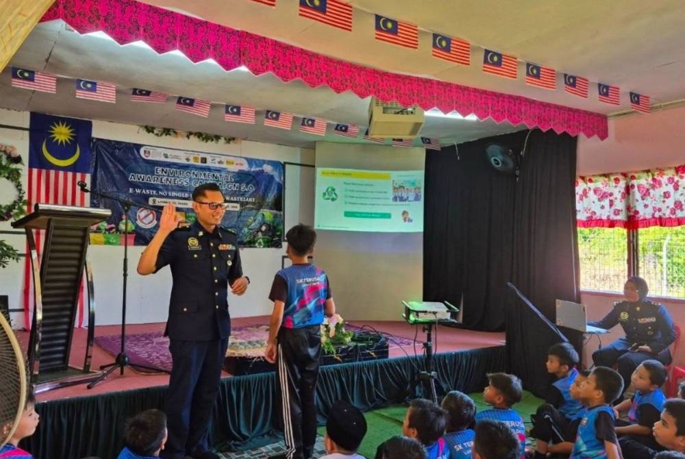 Azman (kiri) memimpin sesi bacaan ikrar bersama murid-murid berkaitan pengurusan e-waste, sebagai komitmen untuk tidak membuang e-waste sewenang-wenangnya serta mengamalkan pelupusan yang betul dan bertanggungjawab.