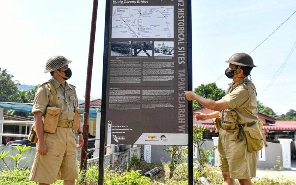 Shaharom Ahmad (right) and Perak Heritage Association secretary Nor Hisham Zulkiflee dressed up as allied soldiers at the signboard during the 80th anniversary commemoration of the Battle of Kampar on Dec 29. (Source: Bernama)
