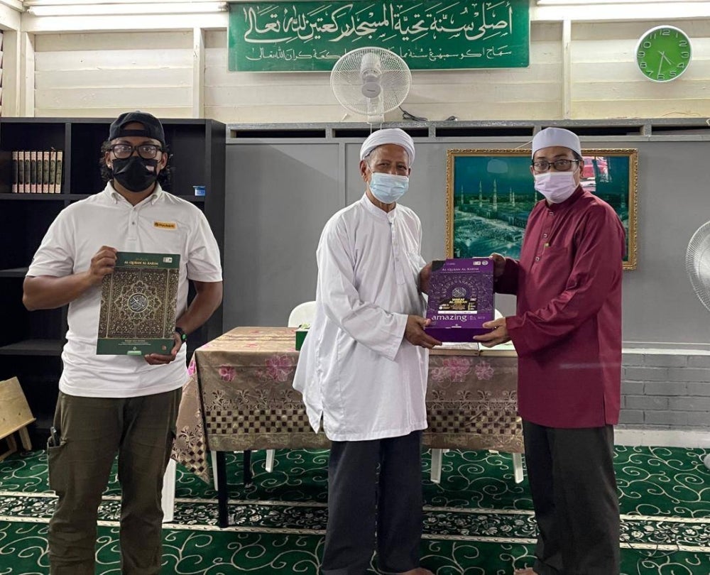 Safri (right) handing over donations to Mohamed (middle) at the al-Hassany surau, witnessed by Jannatul Naim (left).