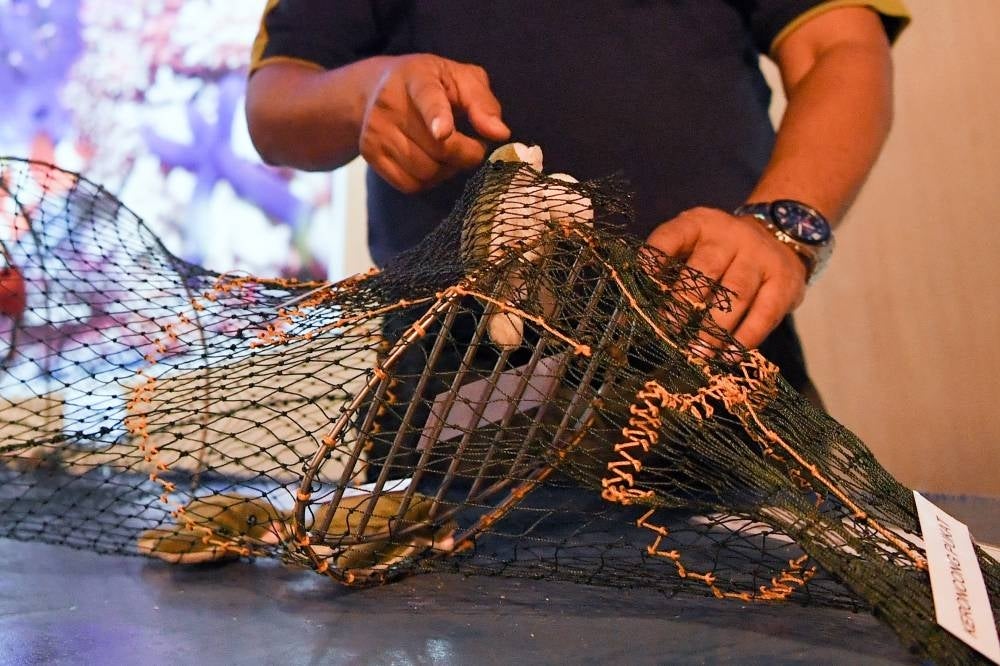 Rantau Abang Fisheries Research Institute (FRI) director Sharum Yusof showing how to use the Turtle Excluder Device fitted into trawl nets throughout the monsoon season.- BERNAMA