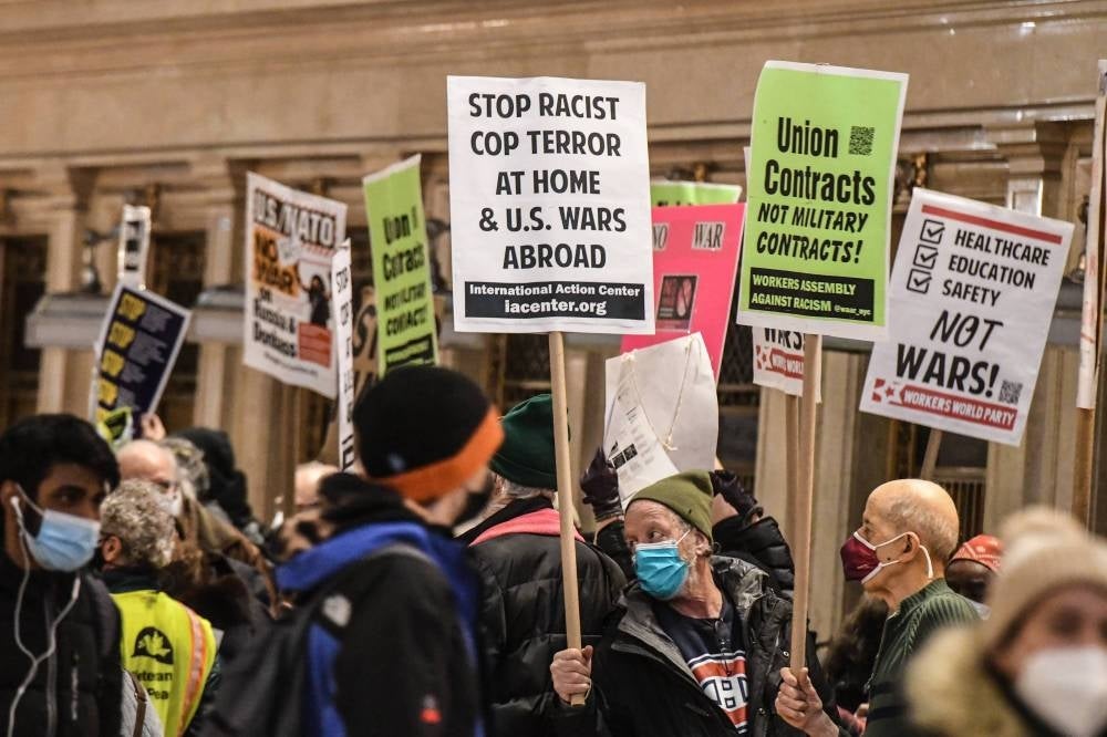 People hold signs and participate in a protest in Grand Central Station in the borough of Manhattan against war in Ukraine on Feb 19, 2022 in New York City. - AFP