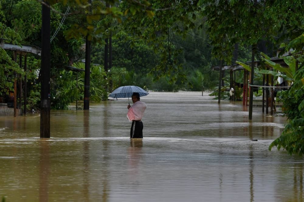 A farm worker waking in flood waters. - BERNAMA