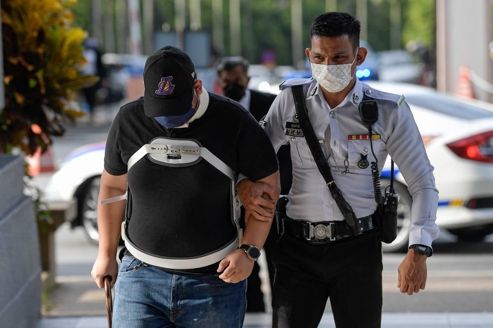Aliff Asyraf Abu, 27, who is in a neck brace and uses a walking stick, pleads not guilty to reckless driving resulting in a road crash that caused the death of four family members on the Sultan Iskandar Expressway, last month. -BERNAMA