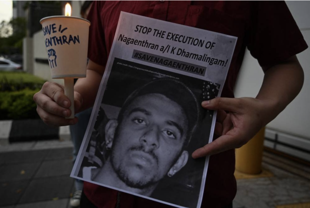 An activist holding a placard attends a candlelight vigil against the impending execution of Nagaenthran K. Dharmalingam, sentenced to death for trafficking heroin into Singapore, outside the Singaporean embassy in Kuala Lumpur on Nov 8, 2021. - AFP