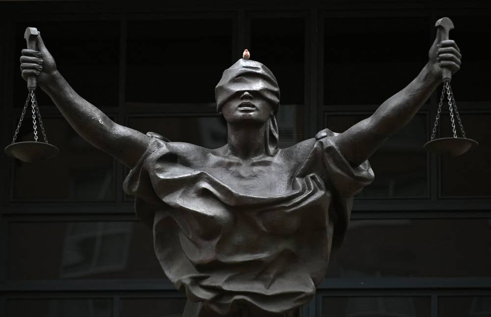 A bird sits on the head of a statue outside the Alexandria federal court house during the trial of IS member El Shafee Elsheikh, the "Beatle", in Alexandria, Virginia, on March 30, 2022. - AFP