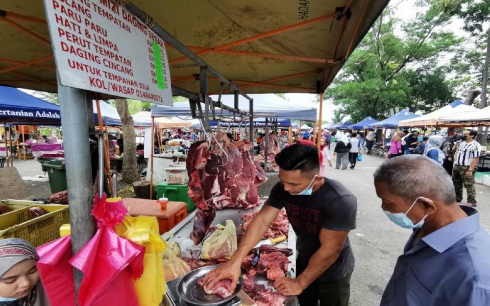 Ahmad Danial Haris (kiri) weighing fresh meat Pasar Tani Hiliran, Kuala Terengganu.