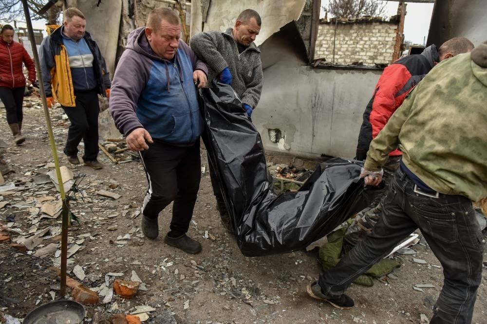 People carry a body of a man killed inside a plastic bag in Andriivka village of Kyiv area, Ukraine, 11 April 2022. - EPA Photo