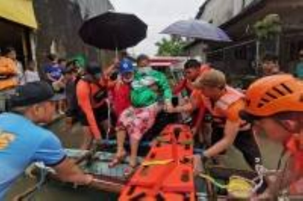 Coast guard and police personnel evacuating a resident from a flooded area in Abuyog town, Leyte province, southern Philippines. Photo - Philippine Coast Guard/ AFP) 