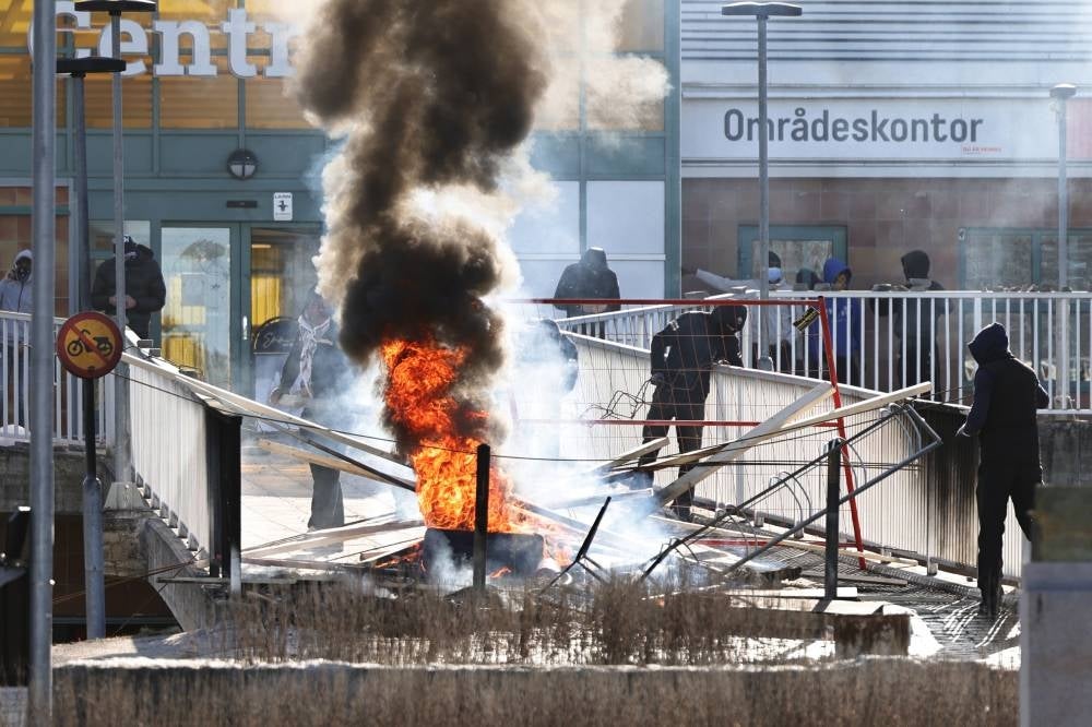 Protesters set fire to a barricade to block access to a shopping area during riots in Norrkoping, Sweden. Pic - EPA/Stefan Jerrevang SWEDEN OUT