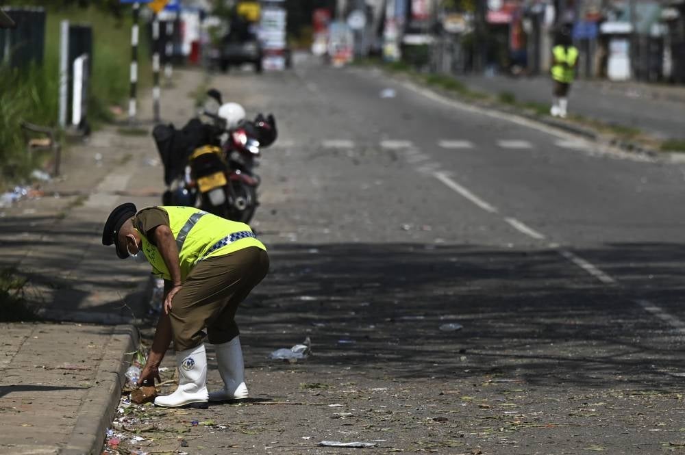 Police officers inspect a road in Rambukkana on April 20, 2022, a day after police killed an anti-government demonstrator while dispersing a protest against the high fuel prices and to demand President Gotabaya Rajapaksa's resignation over the worsening economic crisis.- AFP