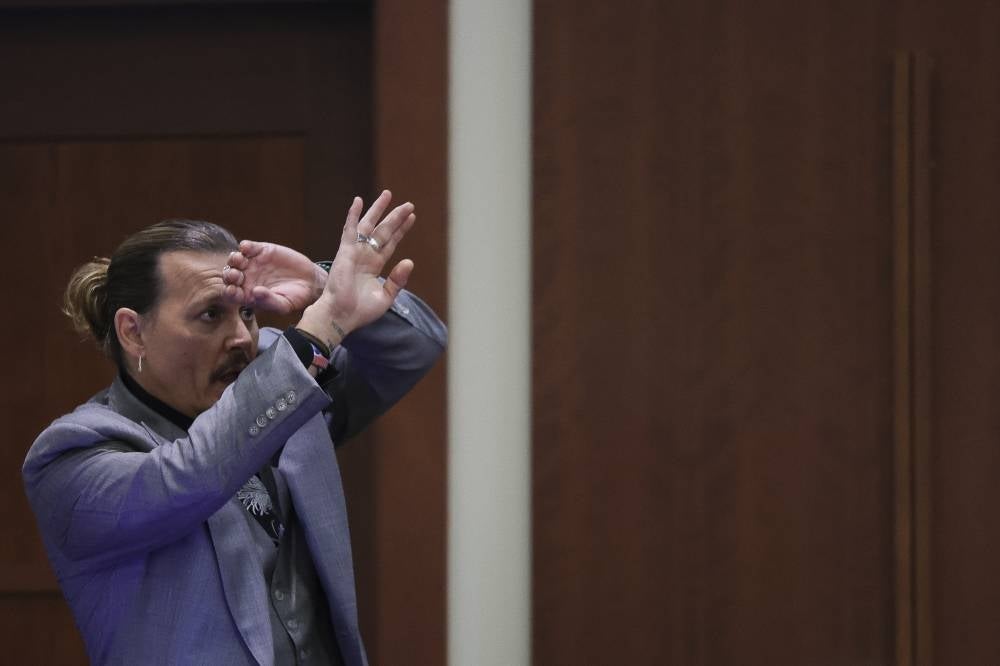 Actor Johnny Depp demonstrates how he claims he shielded himself from an alleged attack by his ex-wife Amber Heard as he testifies during his defamation trial against Heard, at the Fairfax County Circuit Courthouse in Fairfax, Virginia, April 20, 2022. - AFP
