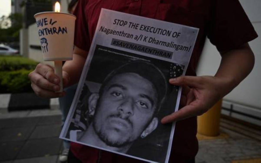 An activist holding a placard attends a candlelight vigil against the impending execution of Nagaenthran K. Dharmalingam, sentenced to death for trafficking heroin into Singapore, outside the Singaporean embassy in Kuala Lumpur on Nov 8, 2021. - AFP
