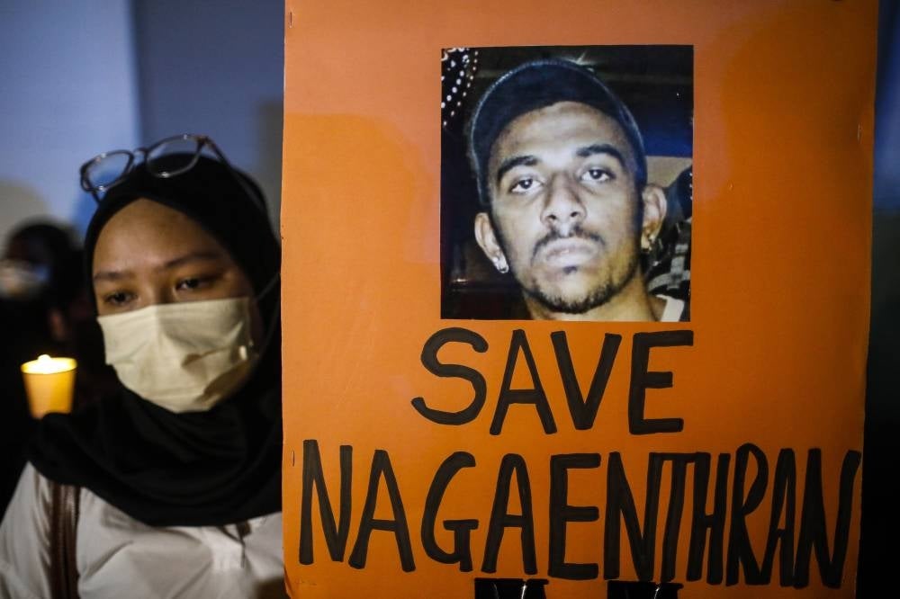 An activist holds a placard and a candle during a candlelight vigil against the death penalty for Malaysian national Nagaenthran K. Dharmalingam, who was convicted of a drug offence 11 years ago in Singapore but diagnosed as intellectually disabled. - EPA